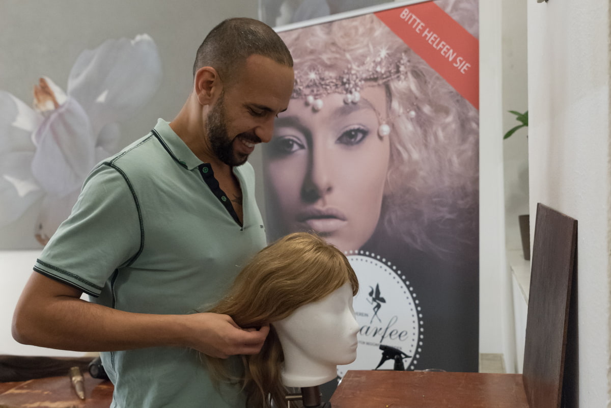Mann stylt eine Perücke im Salon