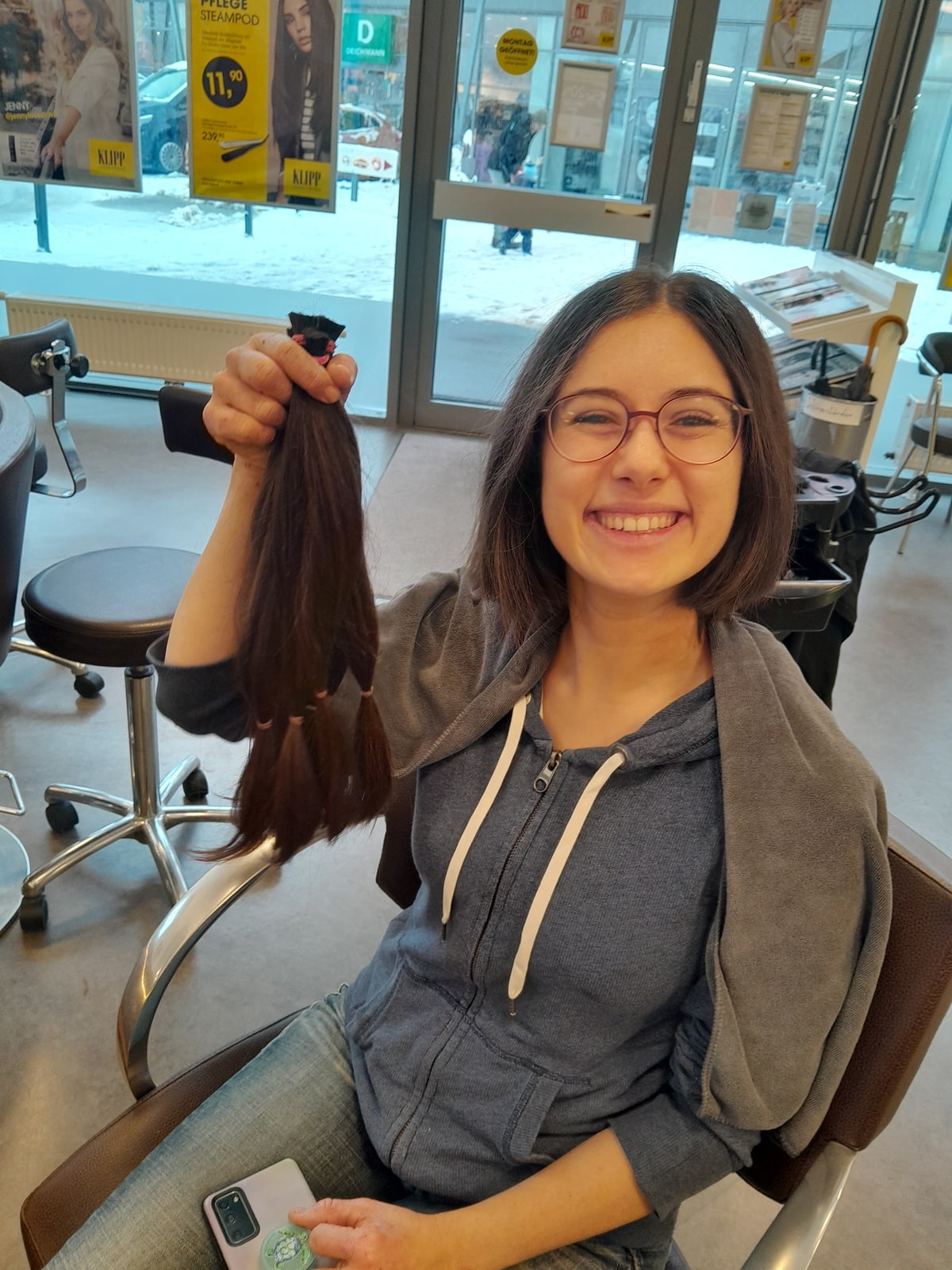 Junge frau lächelt mit einem Zopf Haare in der Hand