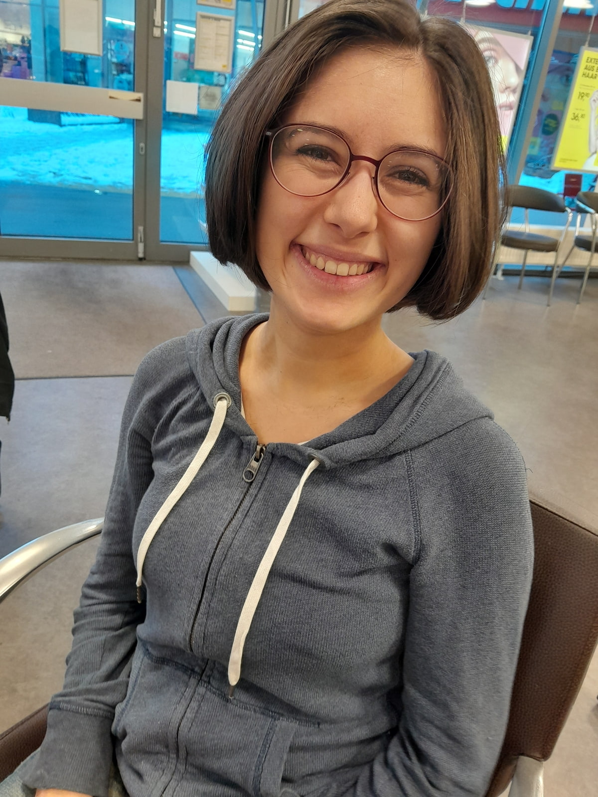 eine junge Frau mit kurzen Haaren lächelt in die Kamera