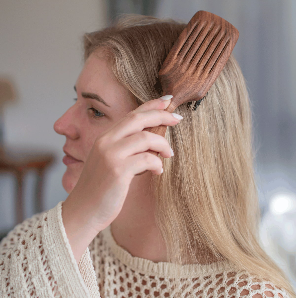 Fettiges Haar Ursachen Frau mit blonden Haaren bürstet ihren Ansatz