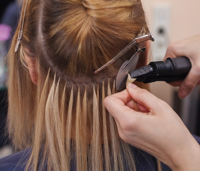 Haarverlängerung Bonding Extensions Friseur bringt Bonding-Extensions an Kopf an