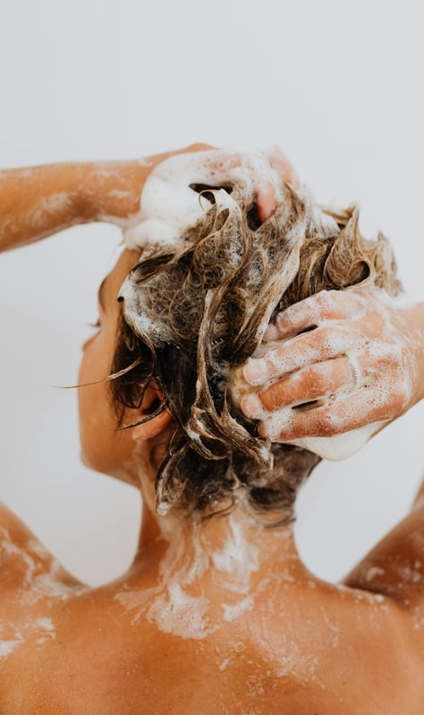 Frau wäscht sich ihre Haare mit viel schäumendem Shampoo
