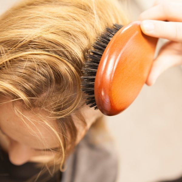 Kopfhautmassagen für gesunde Kopfhaut Seitenaufnahme von blonden Haaren, die gebürstet werden