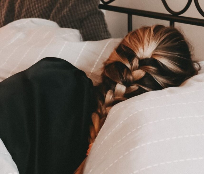 Schonende Pflege für das Haar Frau liegt mit einem geflochtenen Zopf im Bett