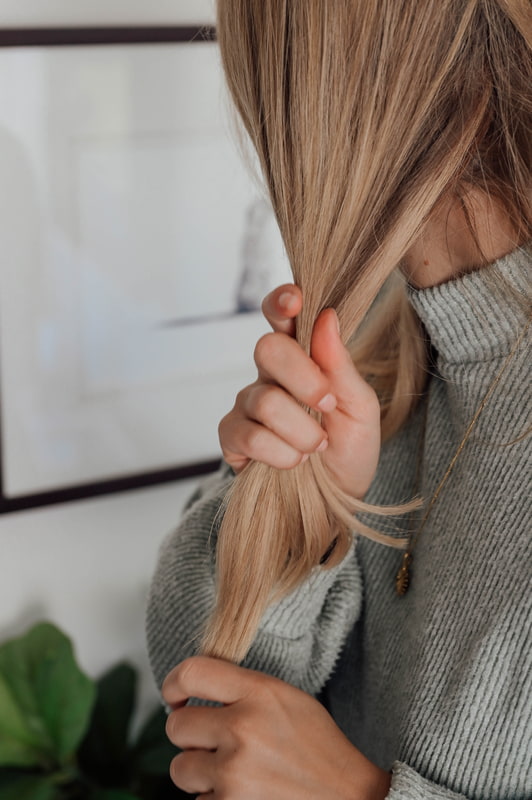 Pflege Winterhaar Frau hält ihr blondes Haar