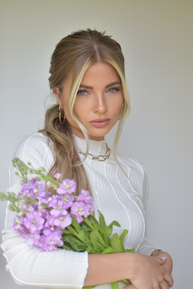 Braided Ponytail Sommerfrisur Frau mit Blumenstrauß im Arm