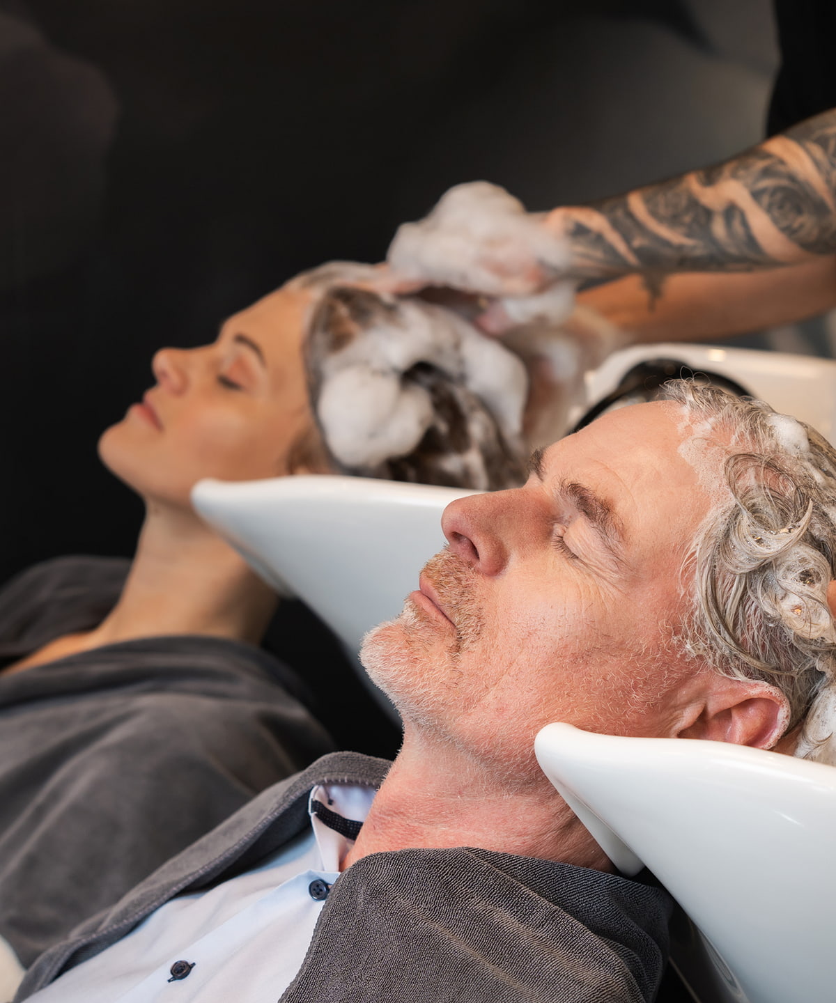 Pflegetipps gesunde Kopfhaut 2 Kunden sitzen in einem Friseursalon und lassen sich die Haare waschen