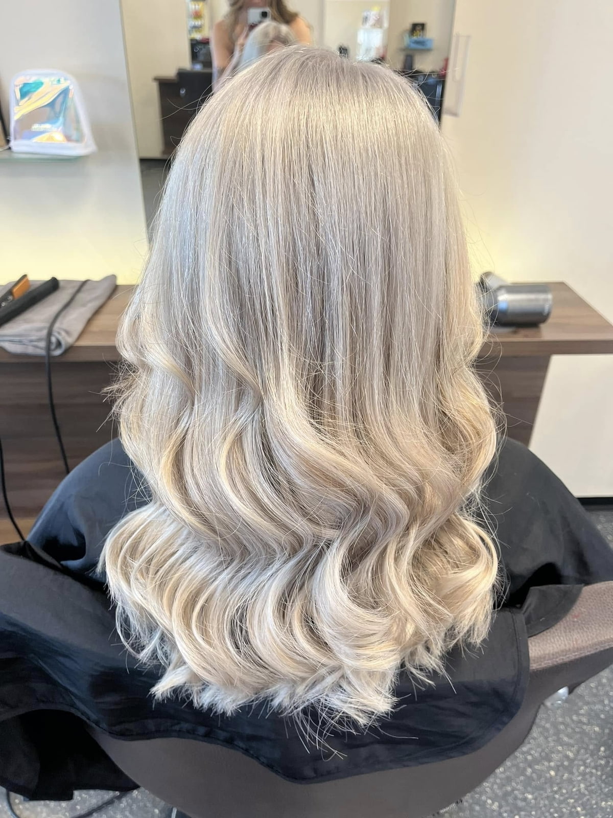 Haarfarbe Platinblond im Salon Frau mit kühl blondierten Haaren sitzt im Friseurstuhl