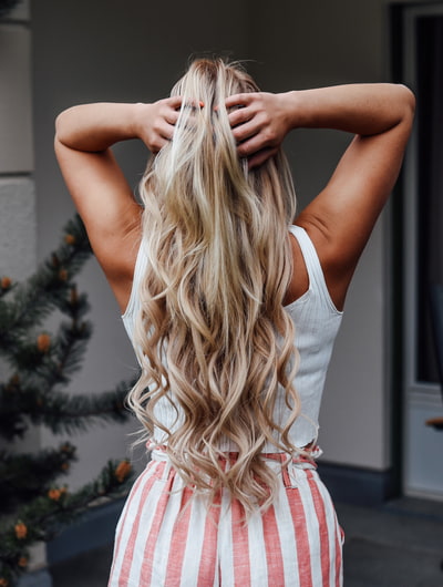 Haarverlängerung so klappt's Frau fährt sich mit den Händen durch die blonden Haaren