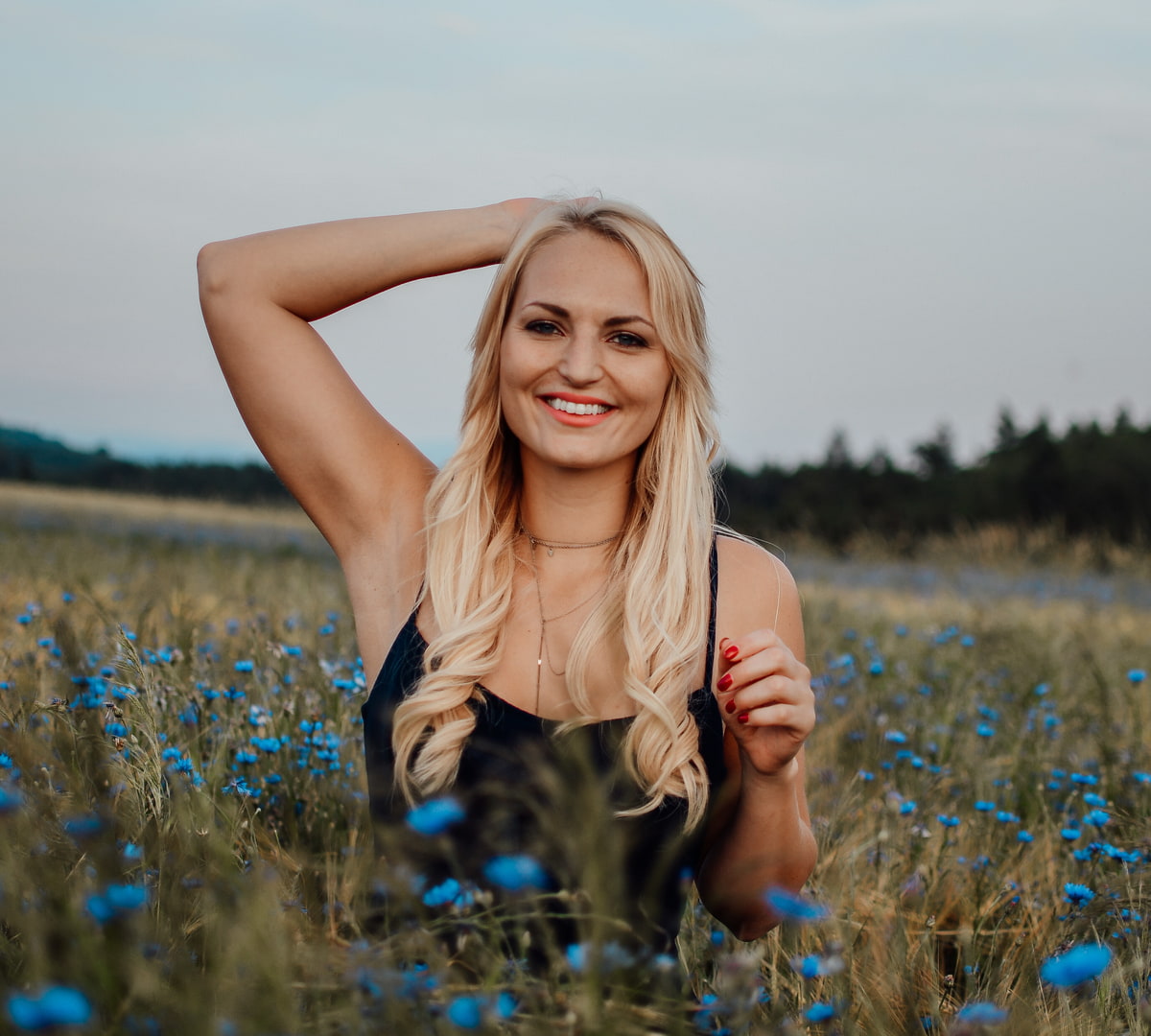 Haarverlängerung bei KLIPP Frau mit blonden langen Haaren steht in einem Kornblumenfeld