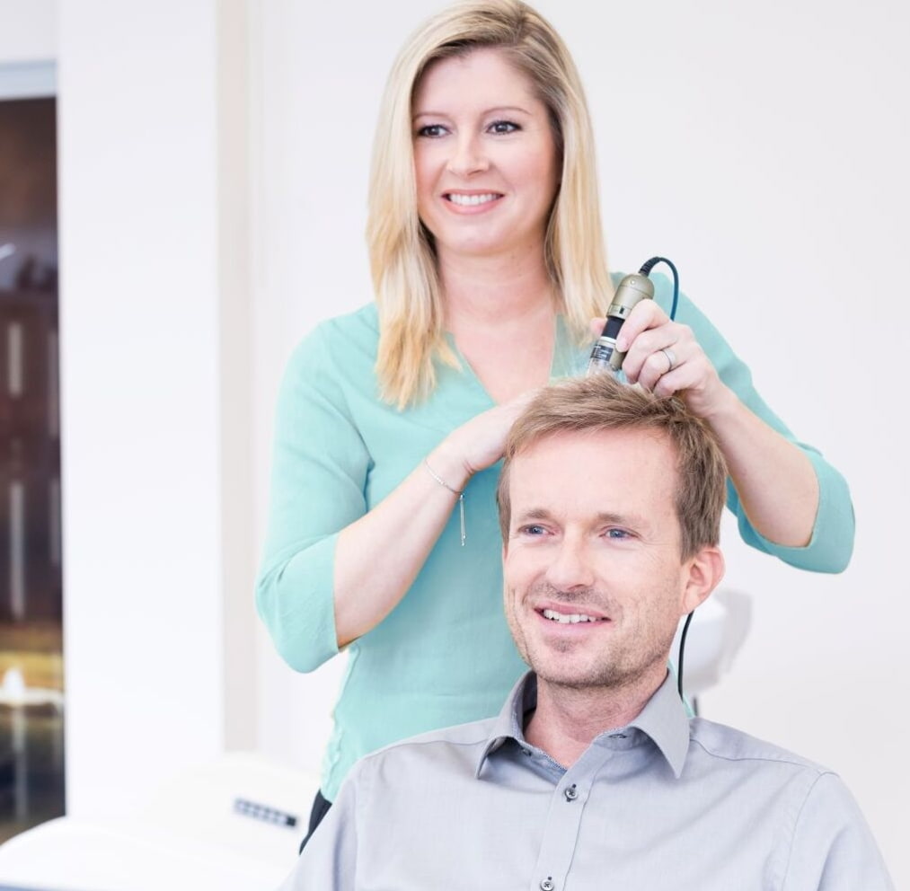 Kopfhautbehandlung bei Haarproblemen Eine Frau berät einen Mann im Salon gegen Haarprobleme