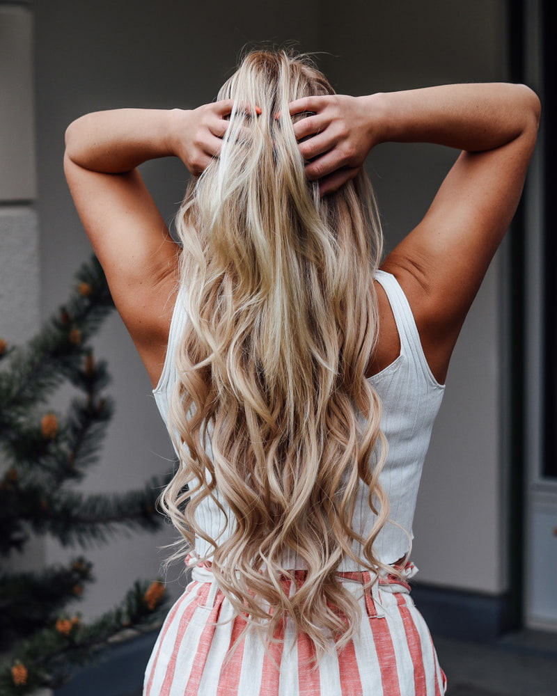 Haarverlängerung so klappt's Frau fährt sich mit den Händen durch die blonden Haaren