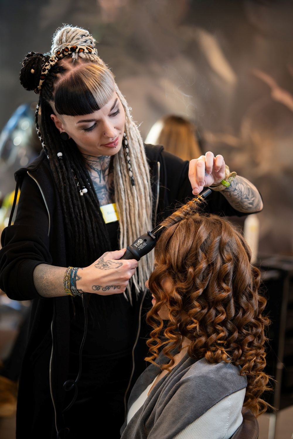 Eine Stylistin lockt einer Frau die Haare 