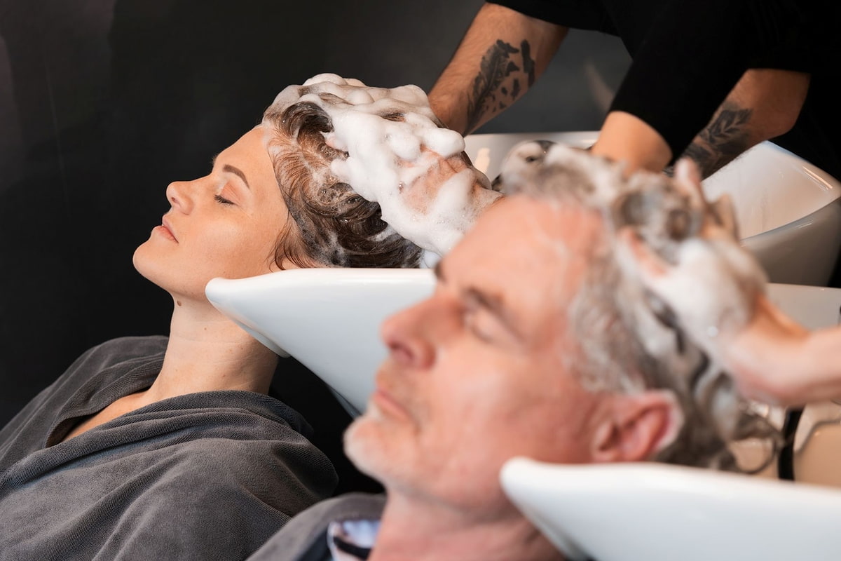 Zwei Kunden genießen Haarwäsche im Salon 