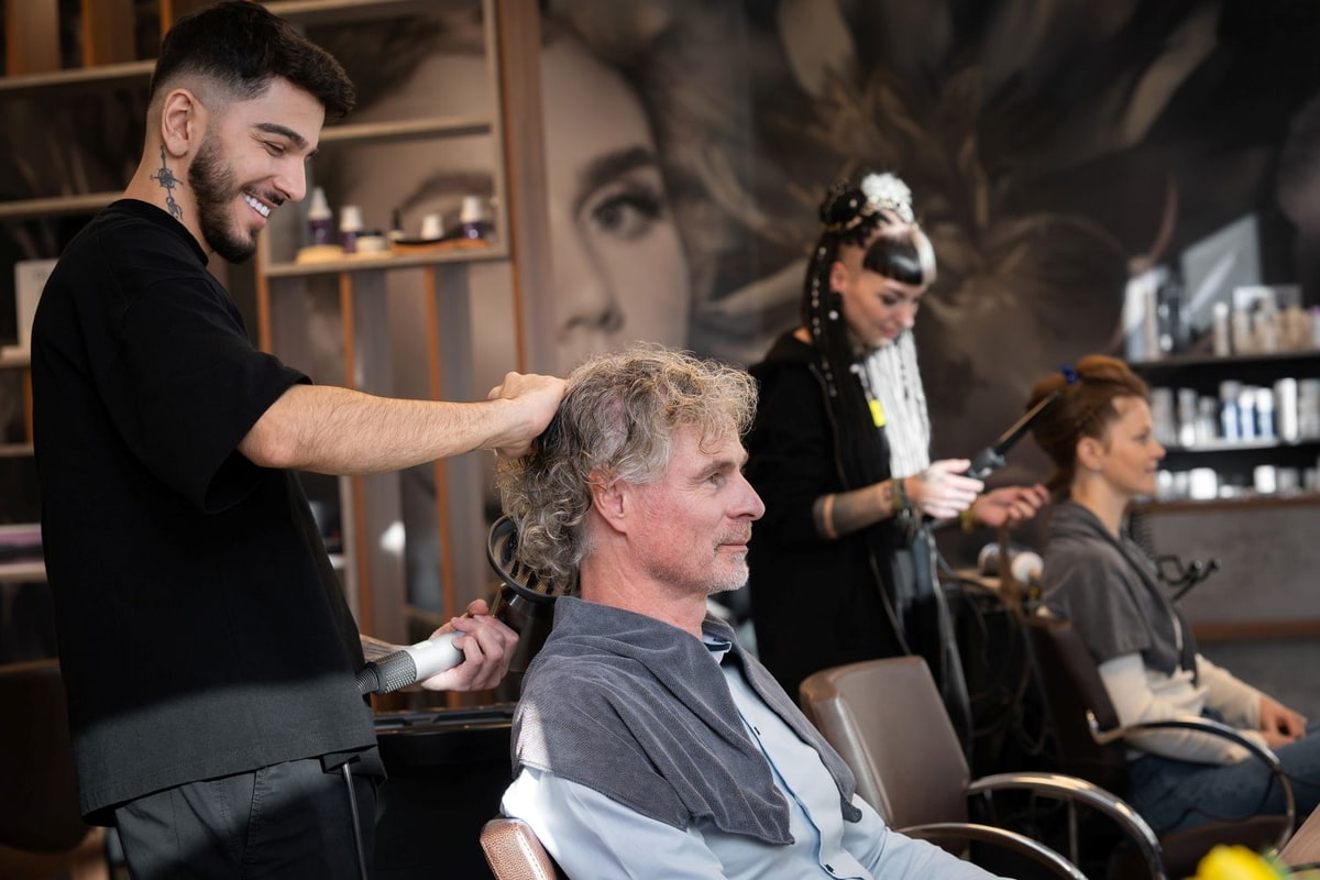 Stylist föhnt die Haare eines Kunden 