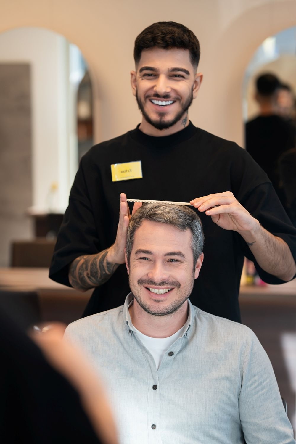 Ein Friseur lacht seinen Kunden an 