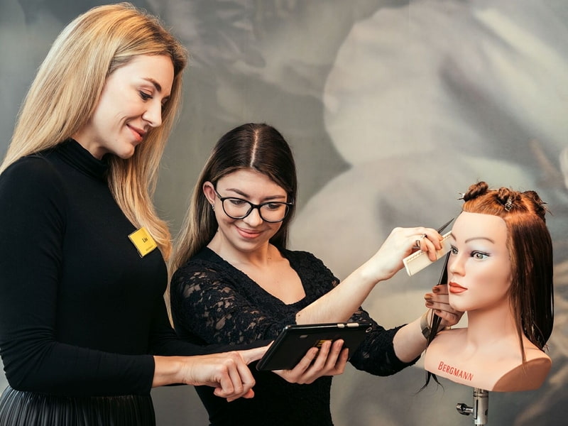 Eine junge Frau bekommt eine Friseurschulung an einem Puppenkopf 