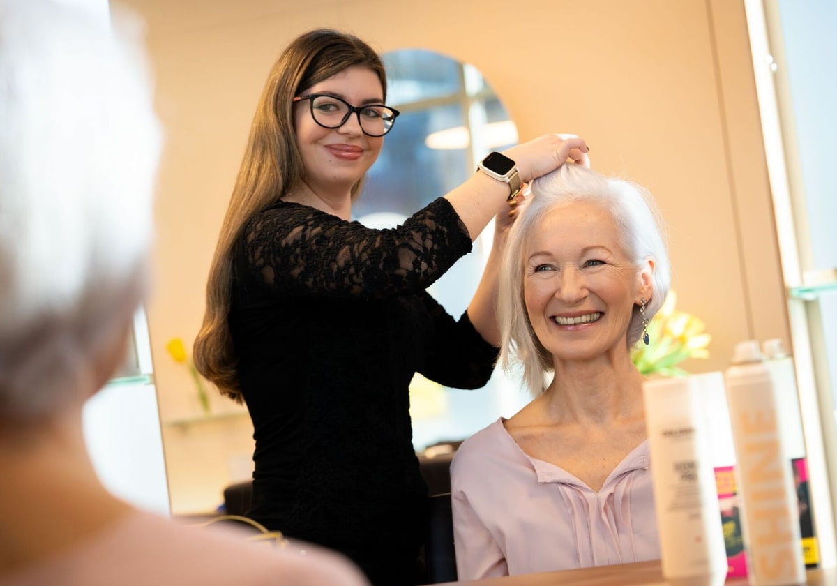 Friseurin schneidet älterer Frau Haare