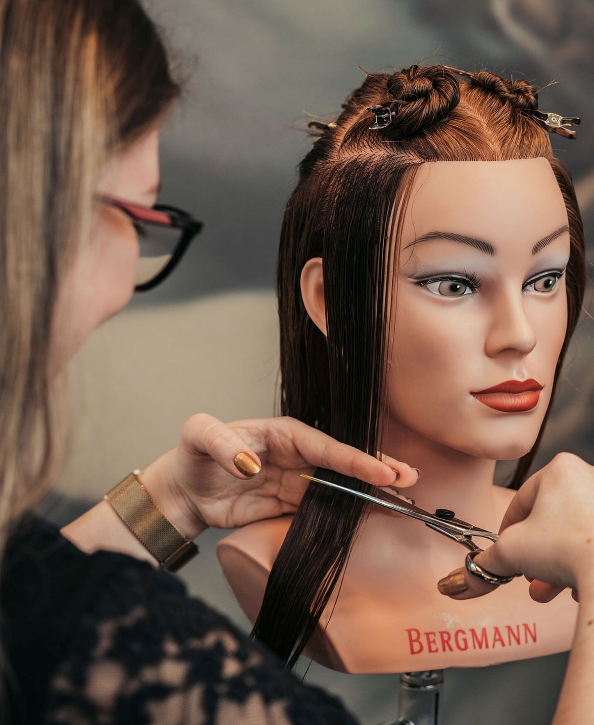 Junge Frau schneidet einem Puppenkopf die Haare