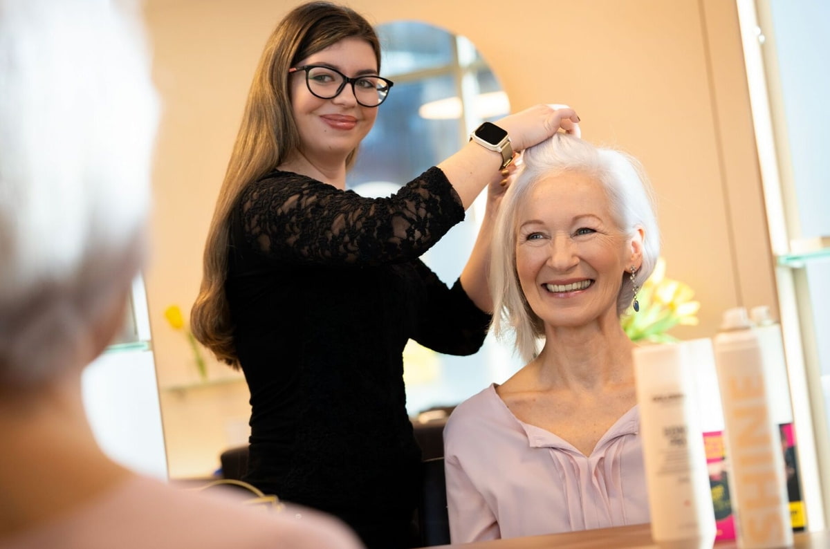 Friseurin schneidet älterer Frau Haare