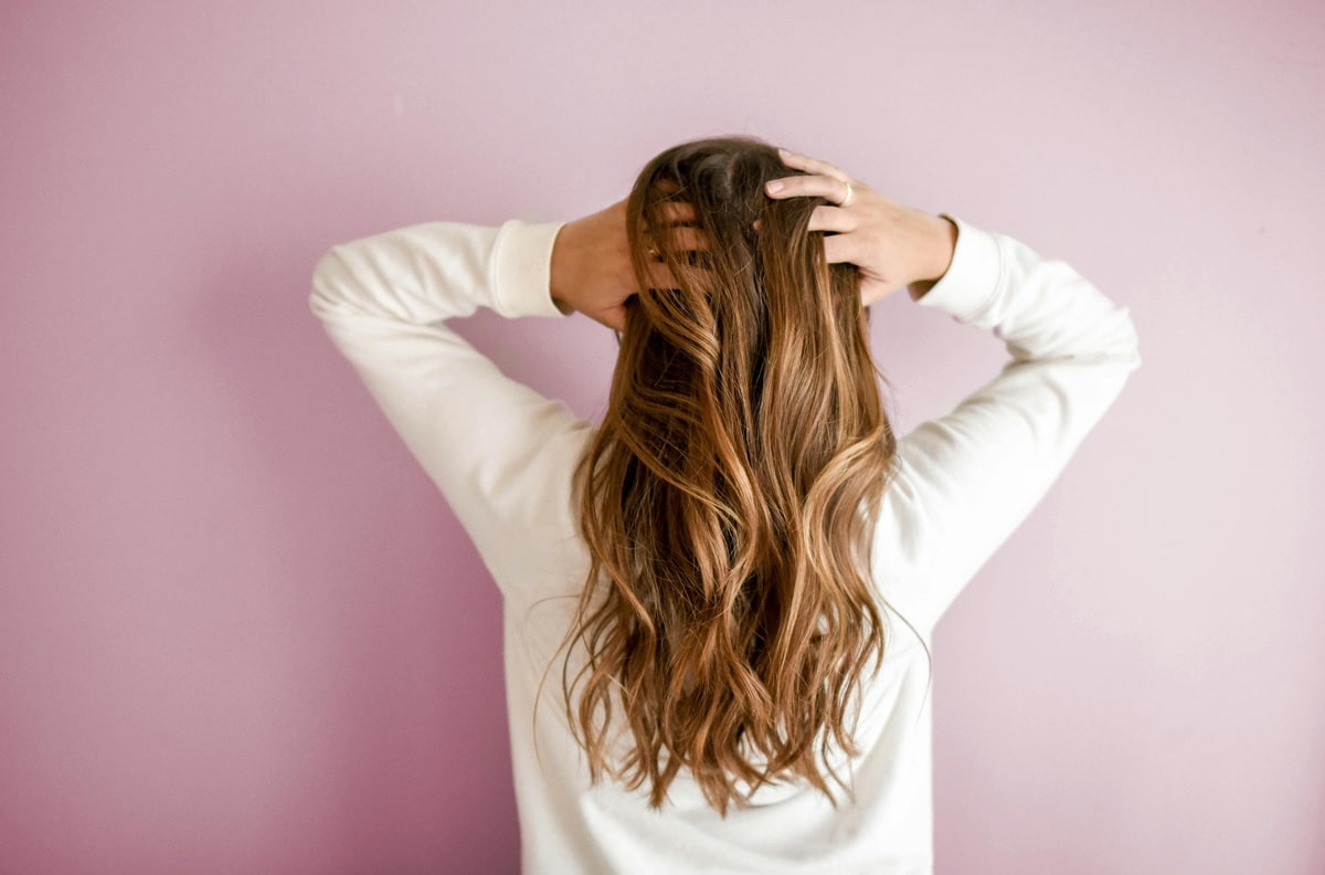 Fettiges Haar Hilfe Frau zeigt ihre Haare von hinten und greift sich durch den Ansatz