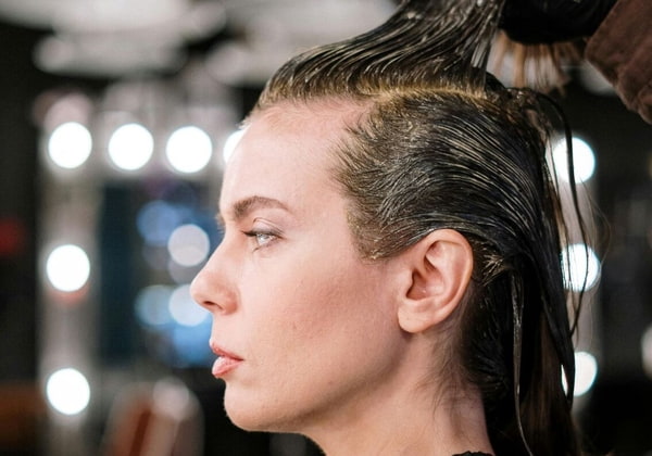 Eine Frau sitzt mit nassen Haaren beim Haarefärben