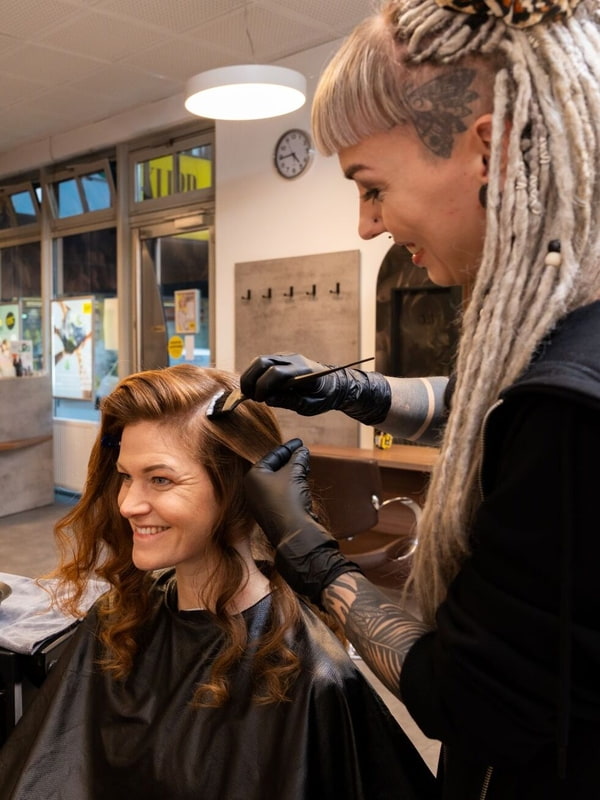 Friseurin färbt einer Kundin den Haaransatz 
